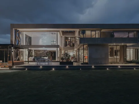 Villa contemporaine au crépuscule, façade vitrée et jardin
